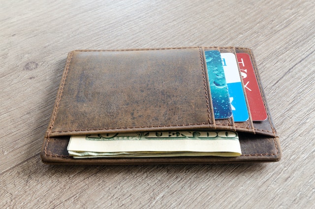brown leather wallet with American cash and credit cards in it